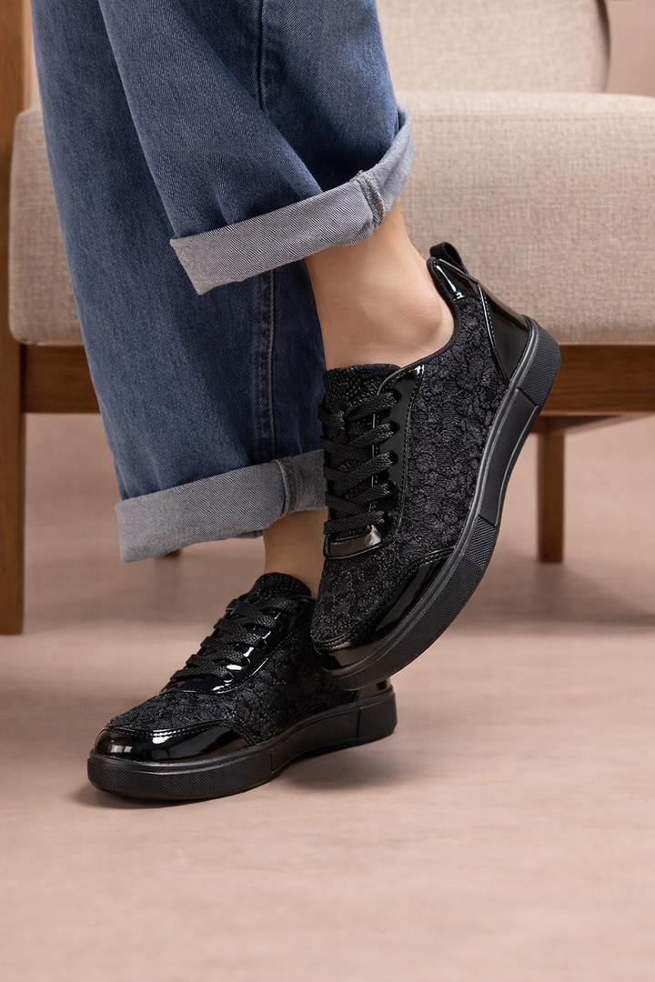 Detailaufnahme: Weiße Damen Sneakers mit feinem Blumenmuster, atmungsaktiv und mit Schnürverschluss.