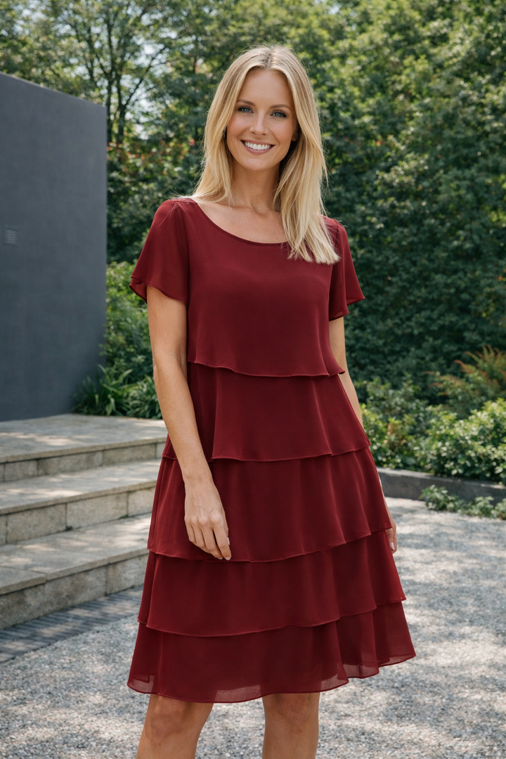 Damen in einem dunkelroten knielangen Rüschenkleid im Garten