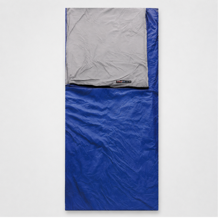 Ein königsblauer Schlafsack im ausgebreiteten Zustand mit grauem Kopfteil auf hellem Untergrund.