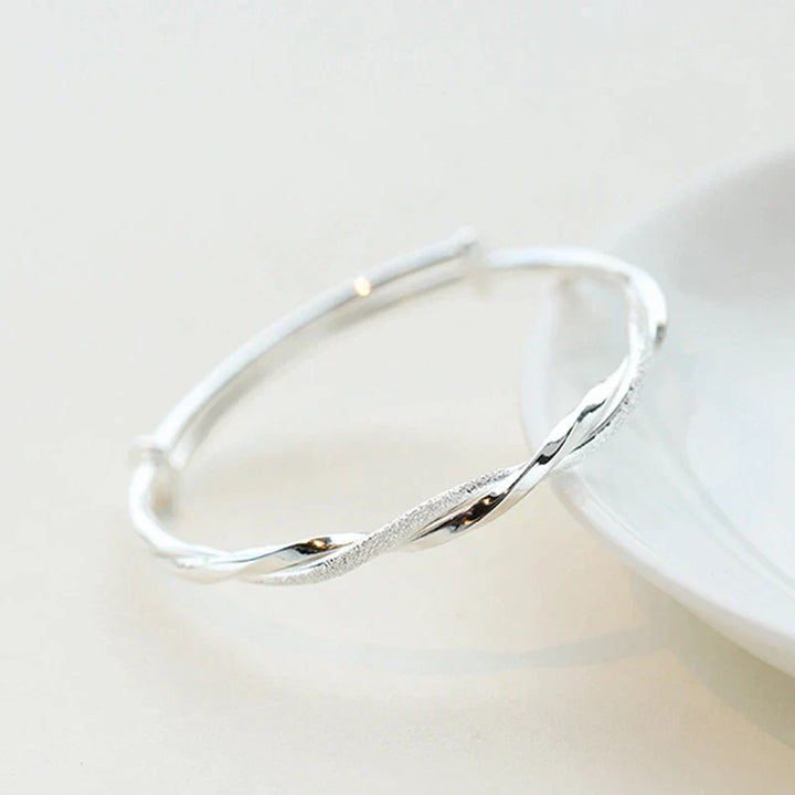 Silberner Armreif, gedrehtes Design, eleganter Schmuck, Damenaccessoire, Geschenkidee.