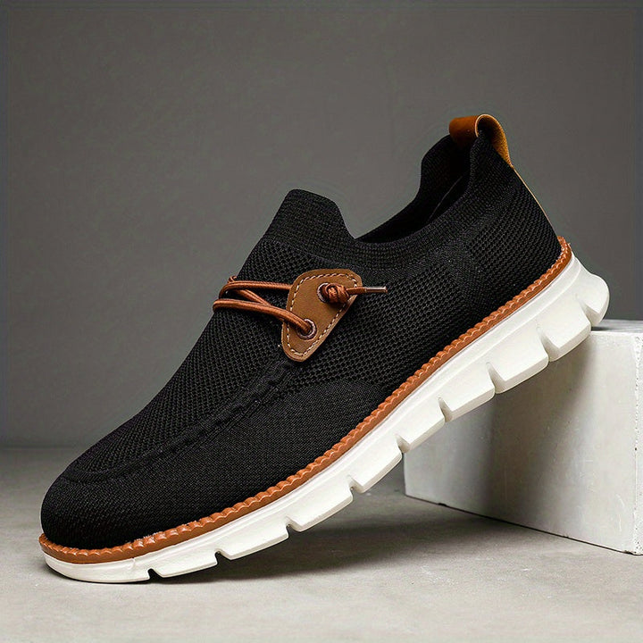 Schwarzer Herren Sneaker in Seitenansicht auf weißem Podest