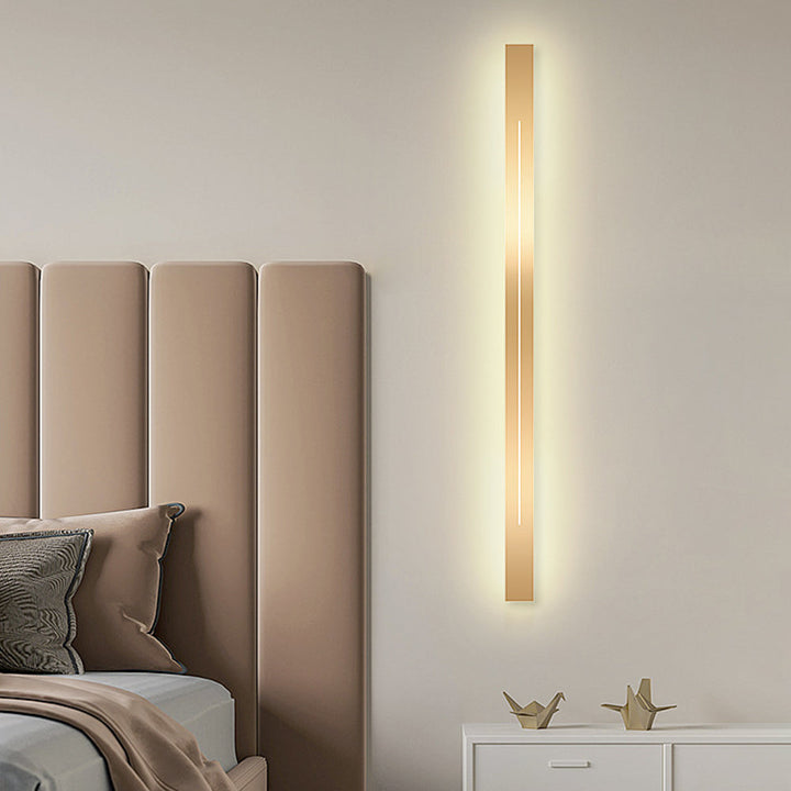 Moderne goldene Wandleuchte im Schlafzimmer, vertikal, LED, minimalistisches Design, beige Wand.