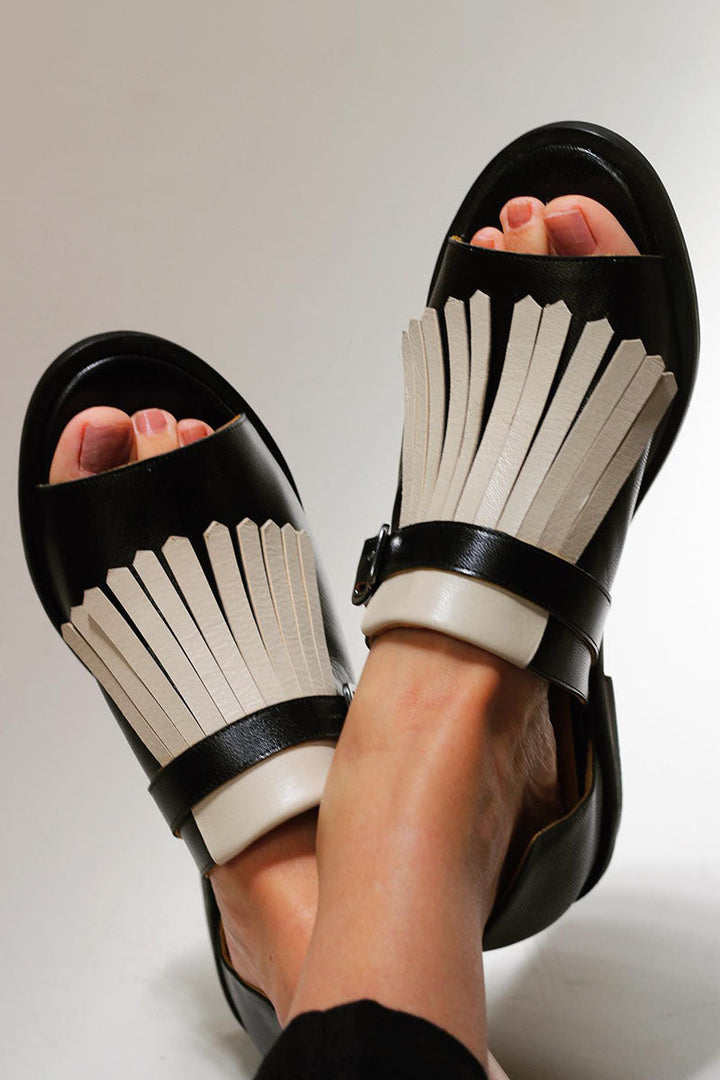 Nahaufnahme der schwarzen Sandalen mit dekorativen Fransen