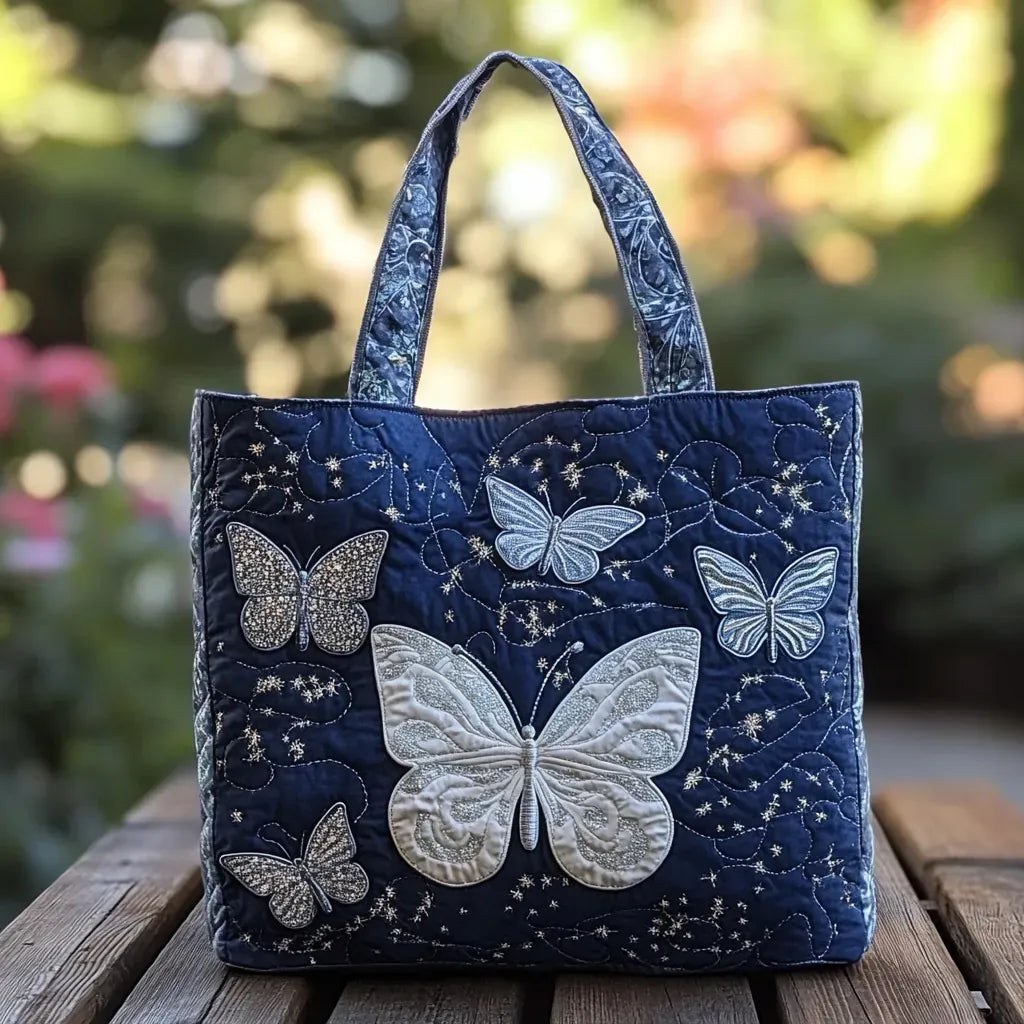 Nahaufnahme einer blauen, gesteppten Damen Handtasche mit silbernen Schmetterlingsapplikationen und Griffen auf einer Holzban