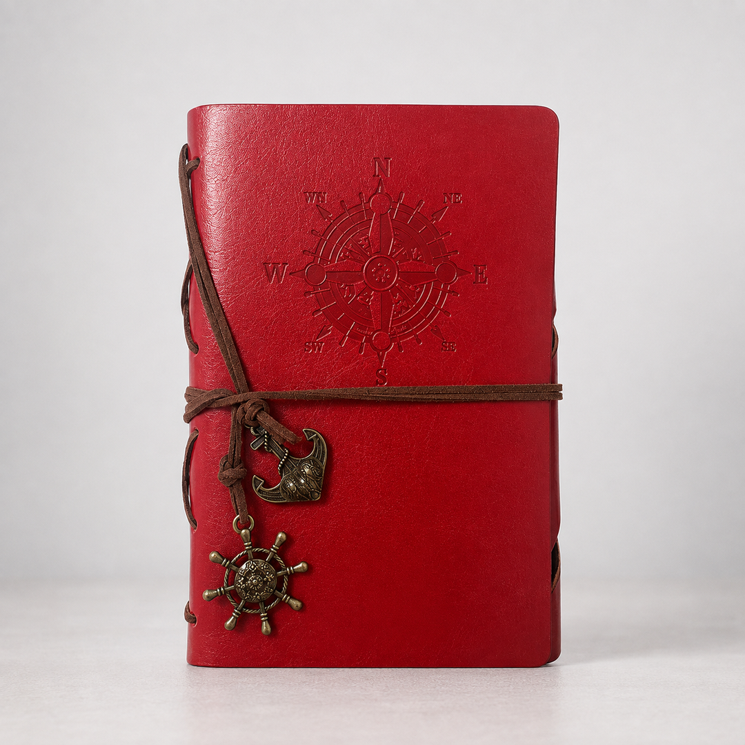 Rotes Vintage-Notizbuch mit Kompass-Motiv und Anker-Anhänger auf hellem Hintergrund