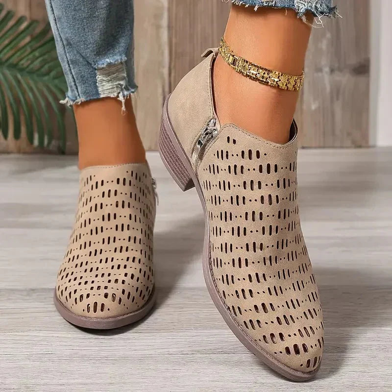Beige Damenstiefel mit seitlichem Reißverschluss und dekorativem Lochmuster an einem Fuß