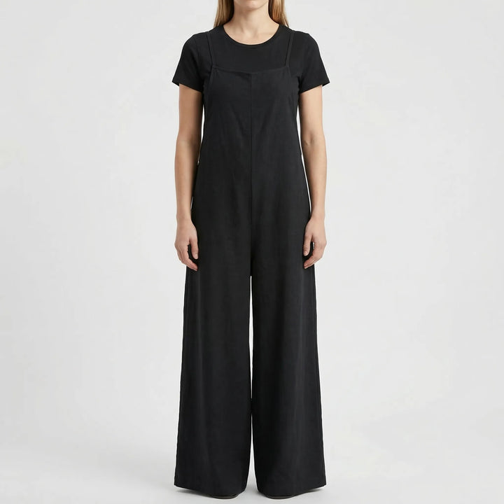 Vorderansicht einer Frau im schwarzen Latz-Jumpsuit mit schwarzem Shirt