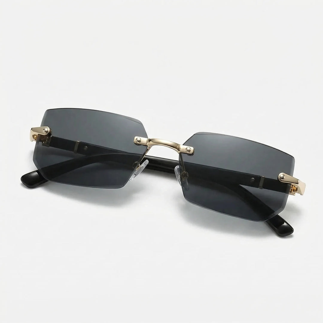 Dunkle rahmenlose Rechteck-Sonnenbrille mit goldfarbenen Details auf hellem Hintergrund