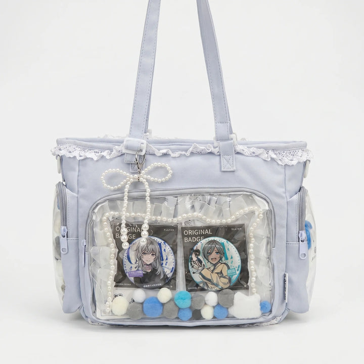 Graue Itabag Umhängetasche mit durchsichtigem Frontfenster und blauen Deko-Elementen vor weißem Hintergrund