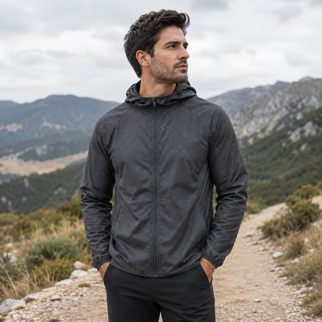 Mann trägt grauen Kapuzen-Windbreaker beim Wandern in den Bergen