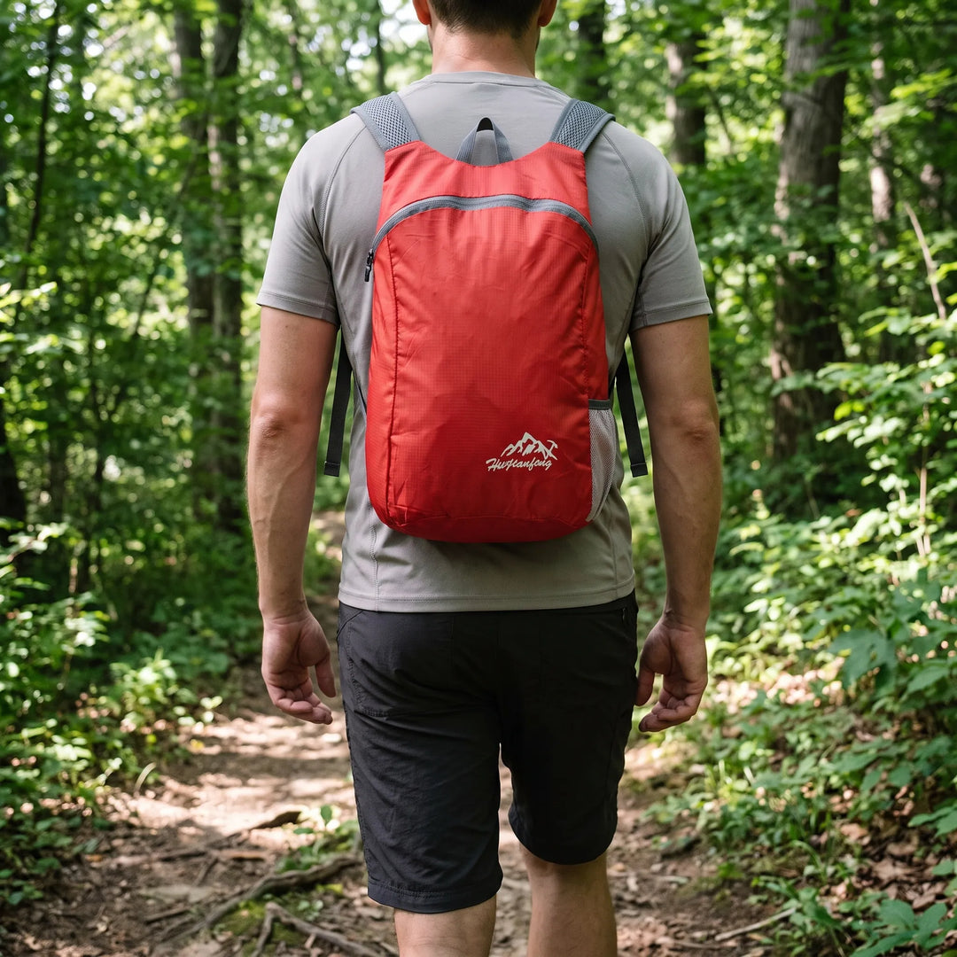 Mann trägt einen roten ultraleichten Tagesrucksack auf einem Wanderweg im Wald