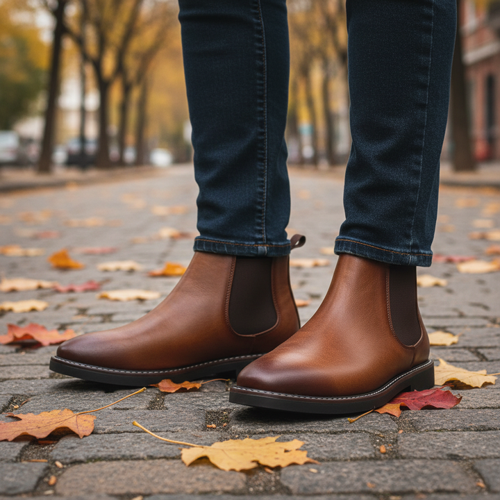 Braune Herren Chelsea Boots im herbstlichen Laub getragen