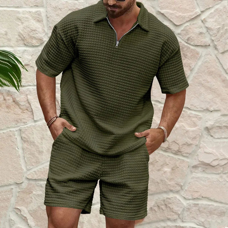 Herren Kurzarm Polo-Set in Olivgrün mit Strukturmuster und Shorts vor einer Steinwand