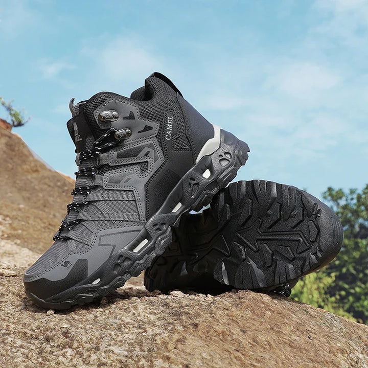 Grauer und schwarzer Herren Trekkingstiefel auf Felsen, Profilsohle sichtbar