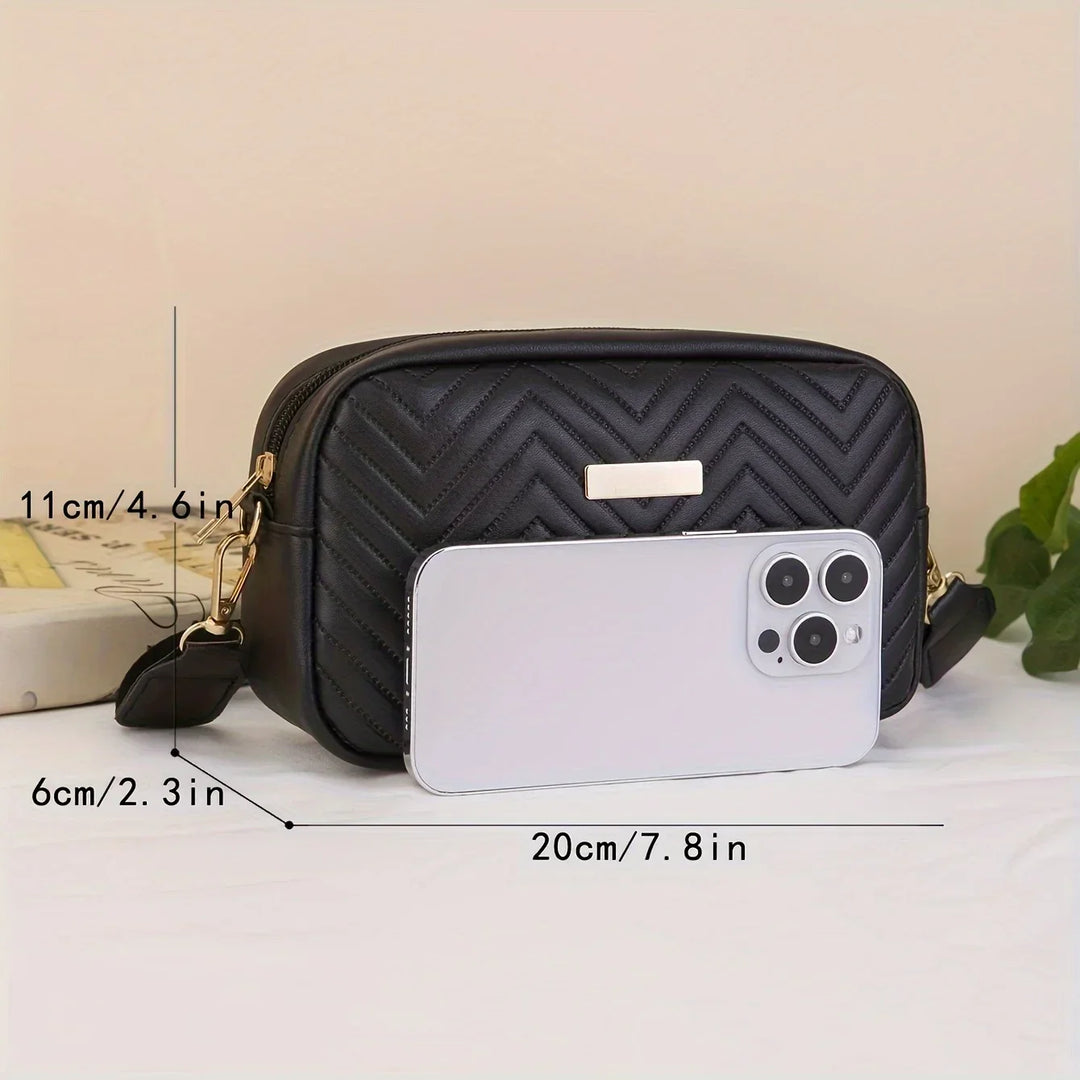 Kompakte schwarze Umhängetasche mit den Maßen 20x11x6 cm neben einem Smartphone zur Größenansicht