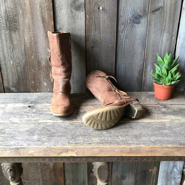 Khakifarbene Damen Stiefel auf Holztisch mit kleiner Pflanze