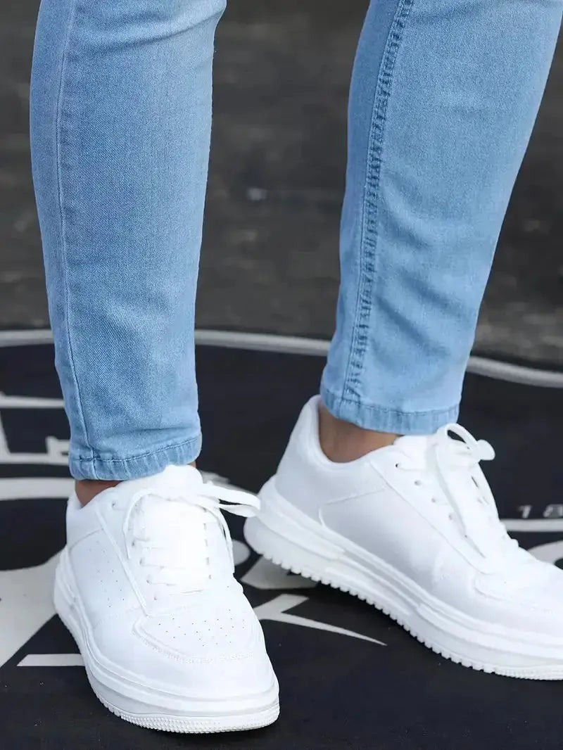 Nahaufnahme der hellblauen Herrenjeans am Bein mit weissen Schuhen