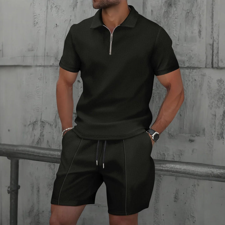 Herren Modell trägt das cremefarbene Polo Set entspannt im Freien.