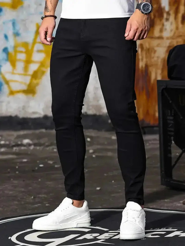Herren trägt schwarze Slim Fit Jeans mit weissen Sneakern