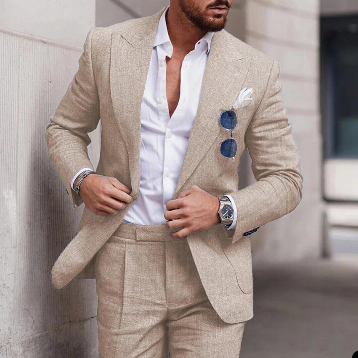 Mann im beigen Leinenanzug mit weißem Hemd und Sonnenbrille, eleganter Herrenmode-Look.