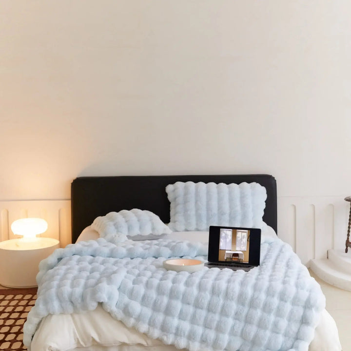 Gemütliches Schlafzimmer mit blauem Bettüberwurf, Tablet auf Bett, moderne Nachttischlampe.