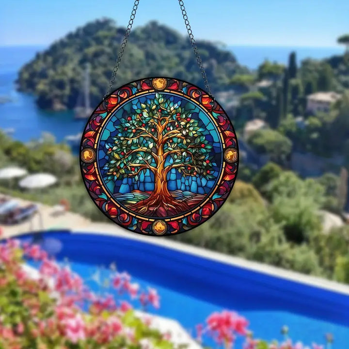Buntes Glasfenster mit Baumdesign, hängend, vor mediterraner Landschaft und Pool.