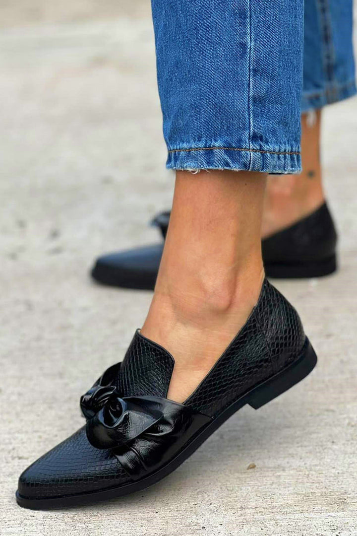 Nahaufnahme der eleganten schwarzen Damenschuhe mit dekorativer Schleife