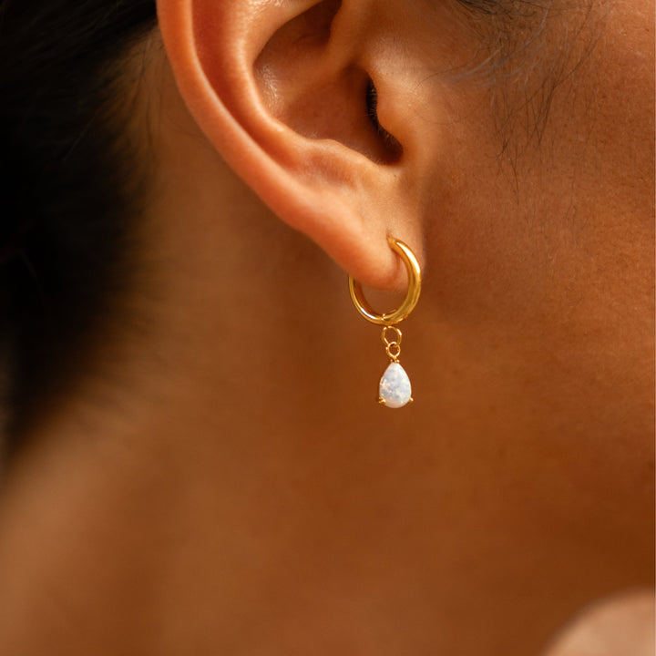 Modischer Damenschmuck: Creolen mit weißem Opal Tropfen als Accessoire
