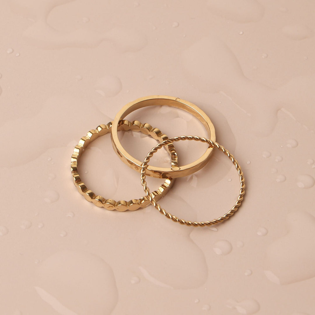 Elegantes goldenes Ring-Set drapiert auf einer nassen Oberfläche