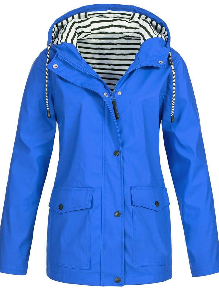 Frau trägt funktionale Damen Outdoorjacke beim Wandern; Schutz vor Wind und Regen in Frühling & Herbst.