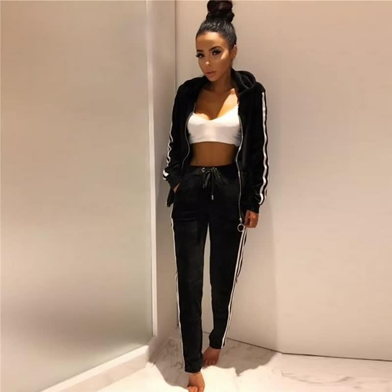 Frau in schwarzem Trainingsanzug mit weißen Streifen, weißem Sport-BH, Freizeitmode.