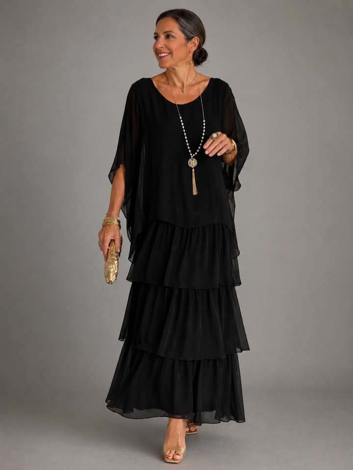 Model in a black flowing maxi dress with layered design