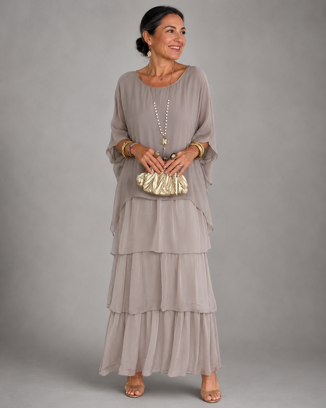 Model in a grey elegant maxi dress holding a gold clutch