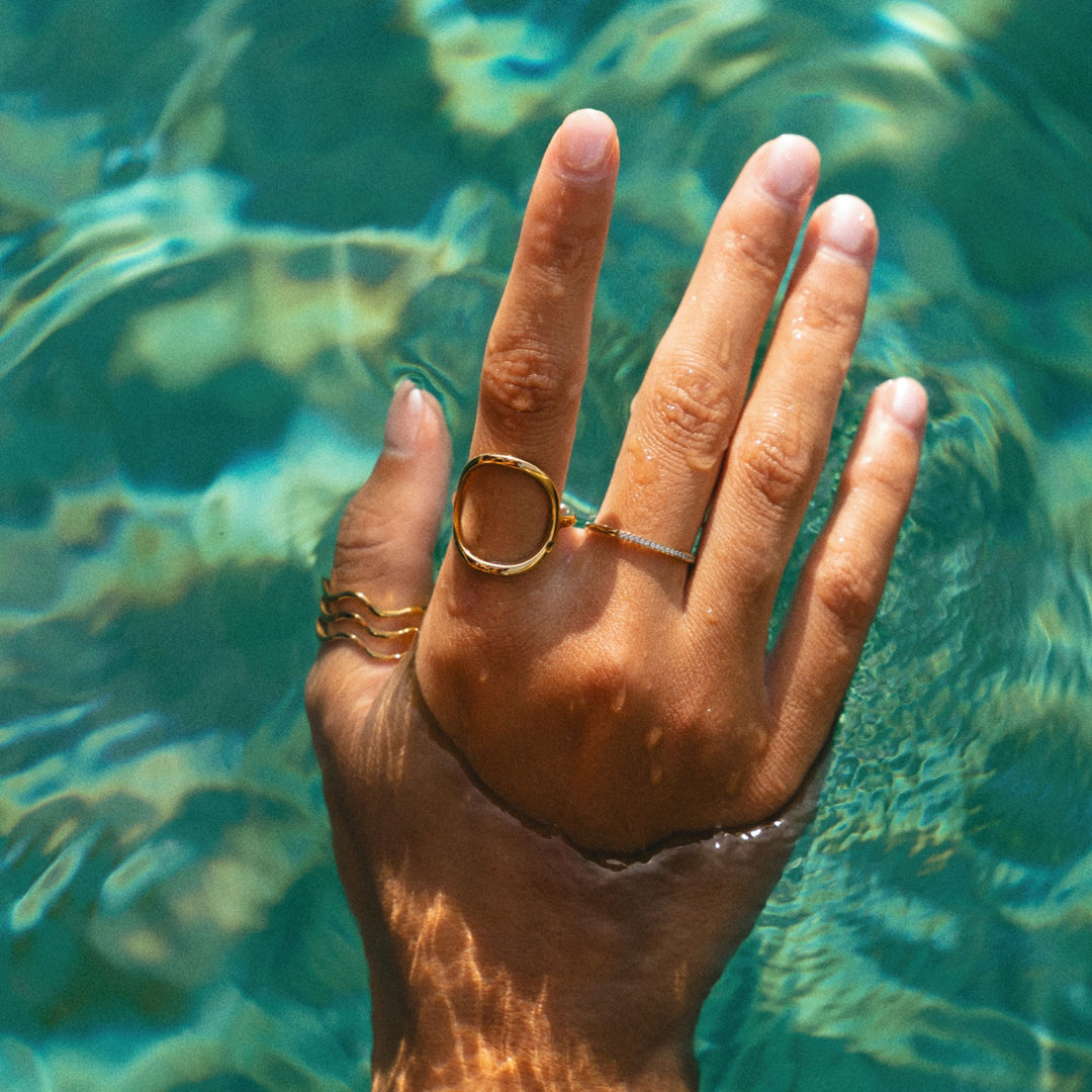 Wasserdichter Zirkonia Ring an einer Hand im klaren Wasser präsentiert