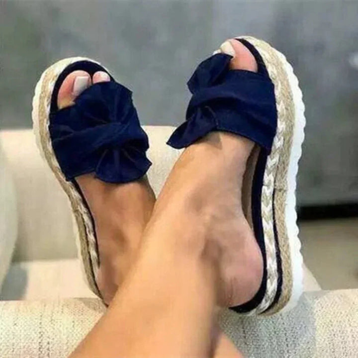 Detail der femininen Schleife auf modernen Damen Plateau Slide Sandalen; modische flache Damenschuhe.