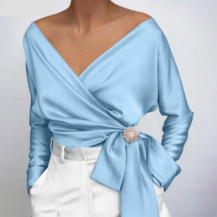 Nahaufnahme der glänzenden Stofftextur einer eleganten Damenbluse. Hochwertige feminine Mode.