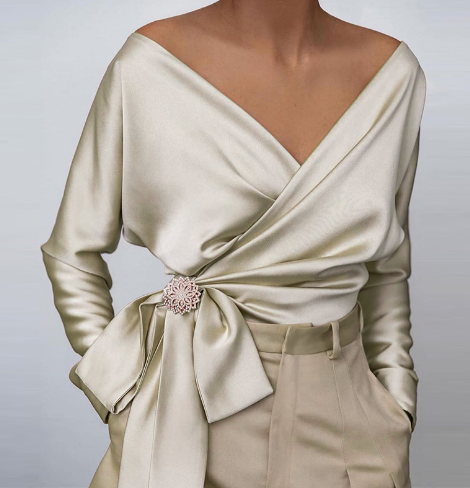Model trägt fließende glänzende Damenbluse. Bequeme und elegante Mode für Frühling und Sommer.