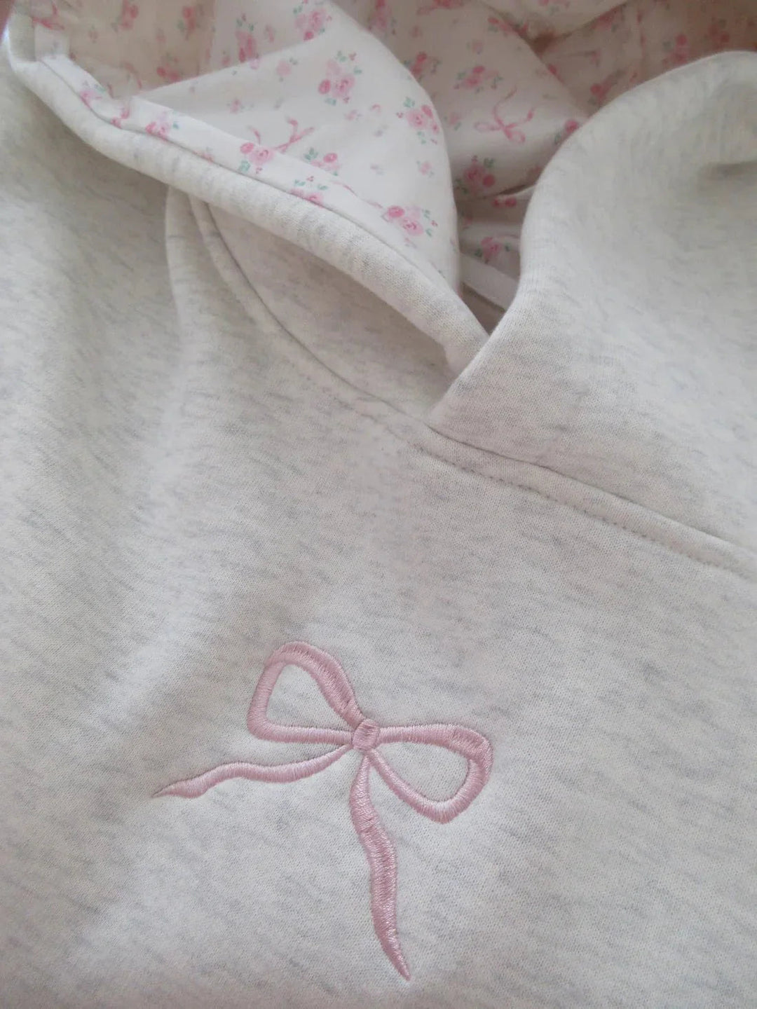 Feminin bequemer Damen Hoodie in Elfenbein mit lockerer Passform und stilvoller rosa Schleife für den Casual Look.