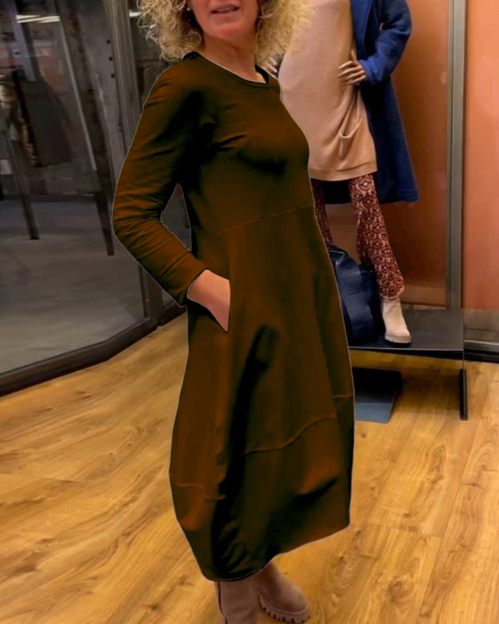 Frau steckt Hände in die Taschen des bequemen Damen Midikleids. A-Linie, Langarm, ideal für Herbst & Winter.