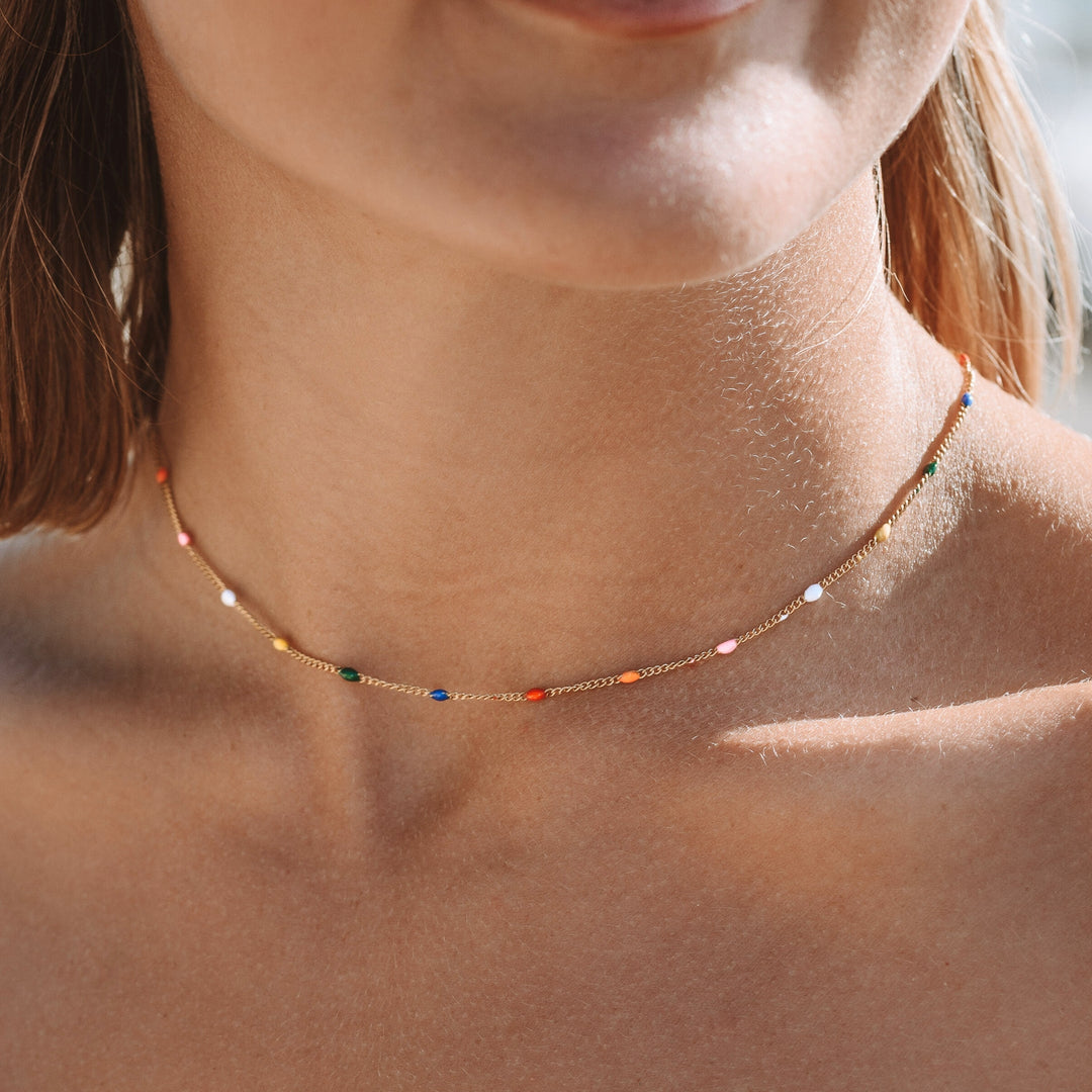 Detailaufnahme des farbenfrohen Chokers mit goldener Kette am Hals