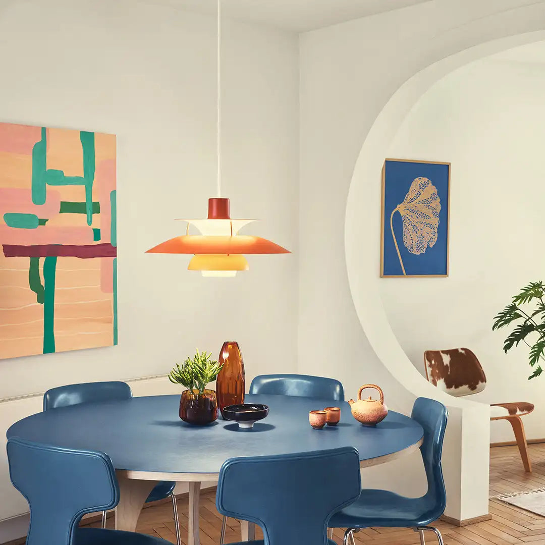 Moderner Essbereich mit blauen Stühlen, rundem Tisch und Designer-Pendelleuchte in stilvollem Interieur.