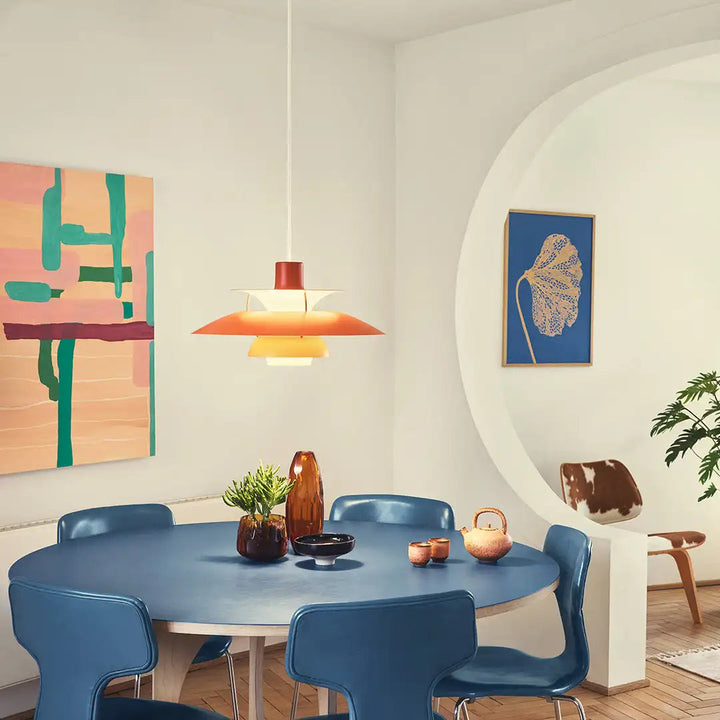 Moderner Essbereich mit blauen Stühlen, rundem Tisch und Designer-Pendelleuchte in stilvollem Interieur.