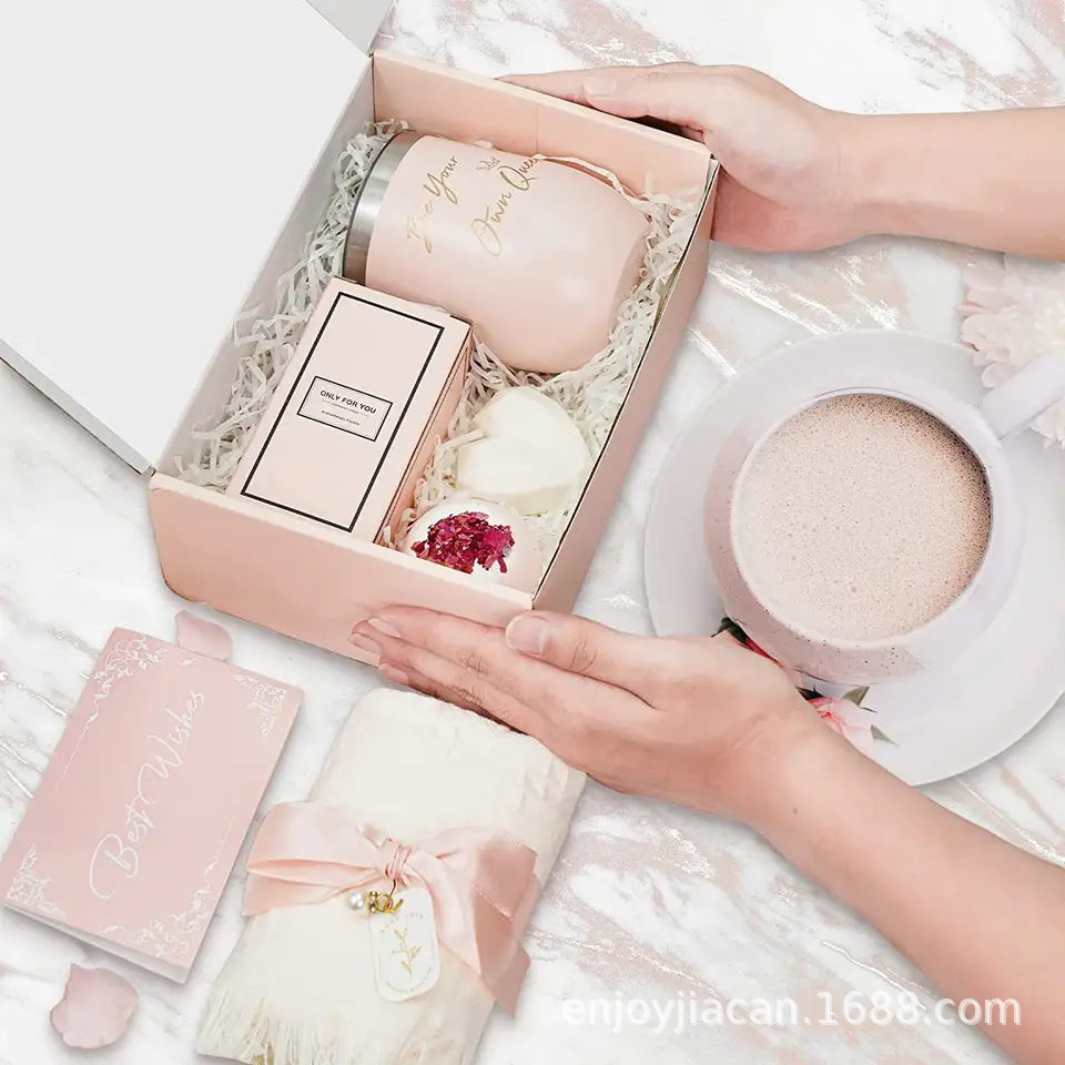 Geschenkbox mit rosa Thermoskanne, Duftkerze, Seife und Karte auf weißem Hintergrund.