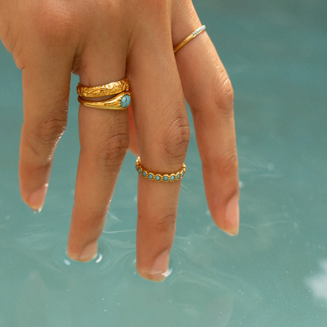 Hand mit goldfarbenem Damenring im Wasser berührend