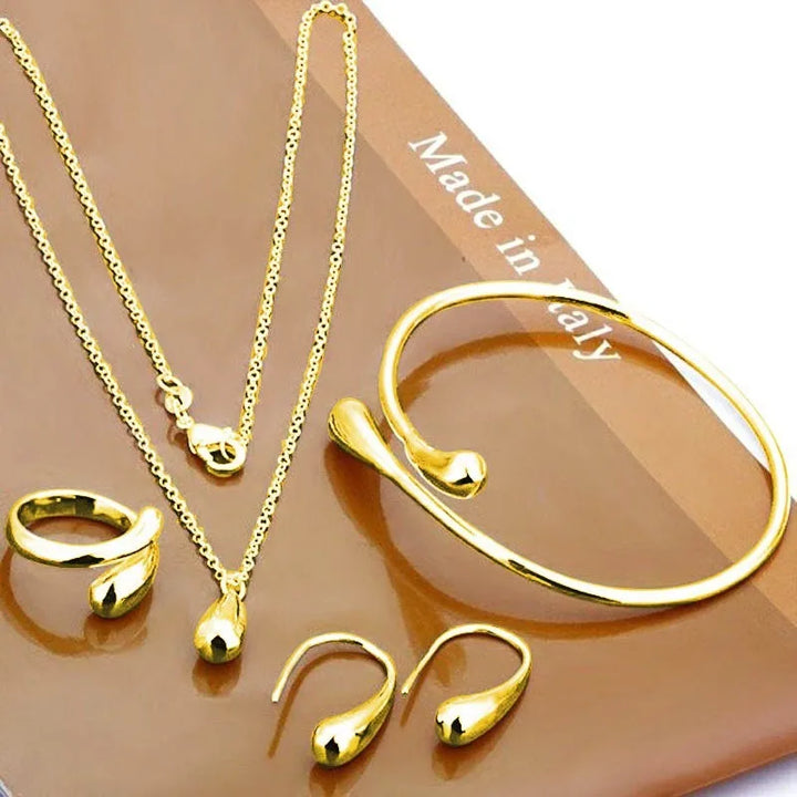 Goldene Schmuckset: Halskette, Armband, Ohrringe, Ringe auf braunem Hintergrund, Made in Italy.