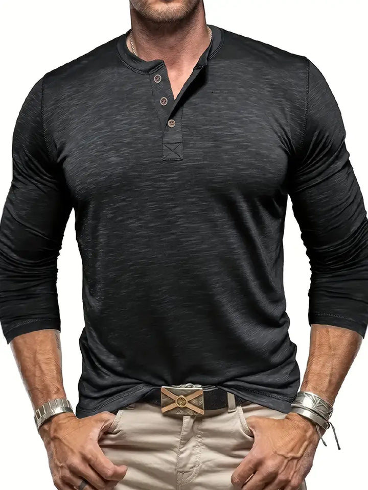 Mann trägt grünes Henley Langarmshirt, bequemes Basic Oberteil, Winter25 Kollektion für Herren.
