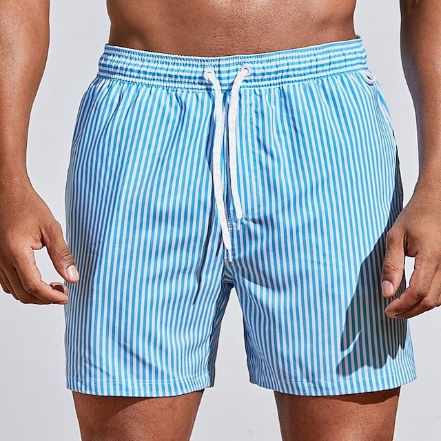 Mann trägt gestreifte Herren Boardshorts am Strand. Perfekte schnelltrocknende Bademode für Urlaub & Freizeit.