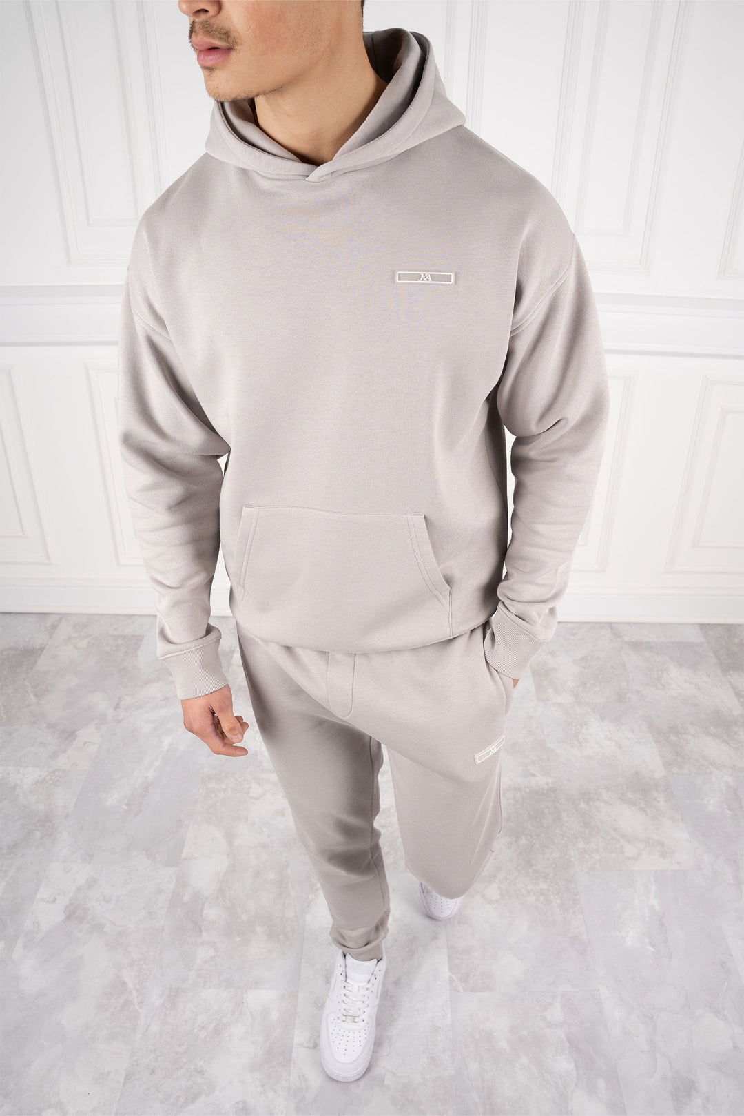 Mann trägt modernen Slim Fit Trainingsanzug mit Kapuze und Hose, ideal für Sport und täglichen Komfort.