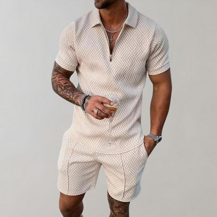 Mann trägt ein leichtes Herren-Sommer-Set mit Poloshirt und Shorts am Strand, bereit für den Urlaub.