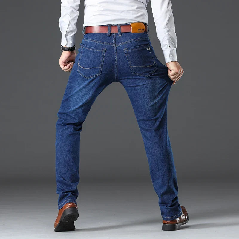 Modell trägt klassische Herren Stretch-Jeans, dunkelblau, kombiniert Stil und Bewegungsfreiheit für den Tag.